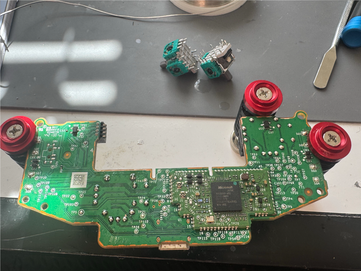 Xbox controller circuit board and removed joystick modules during a Hall-effect upgrade
